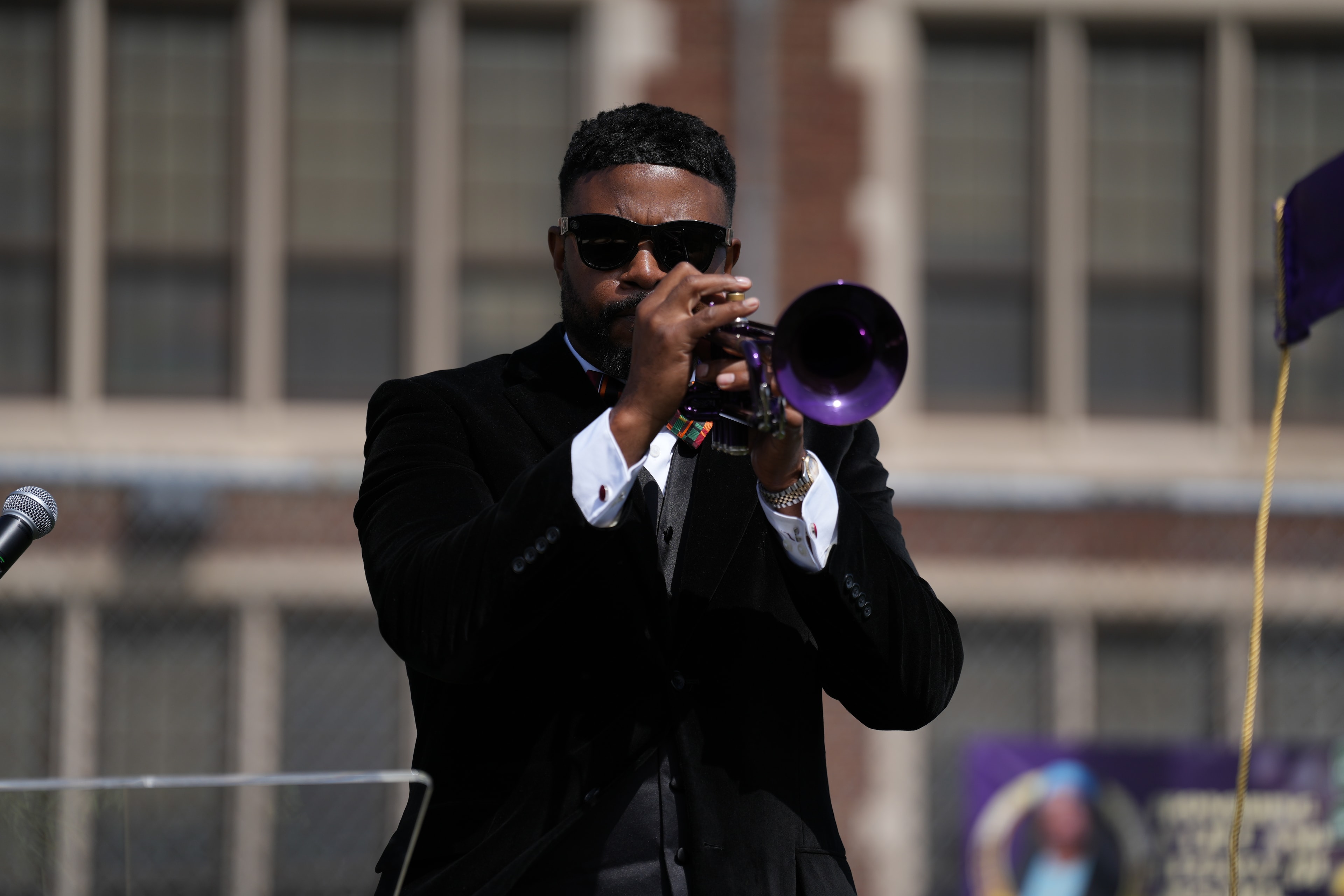 Man in suit playing purple trumpet outdoors