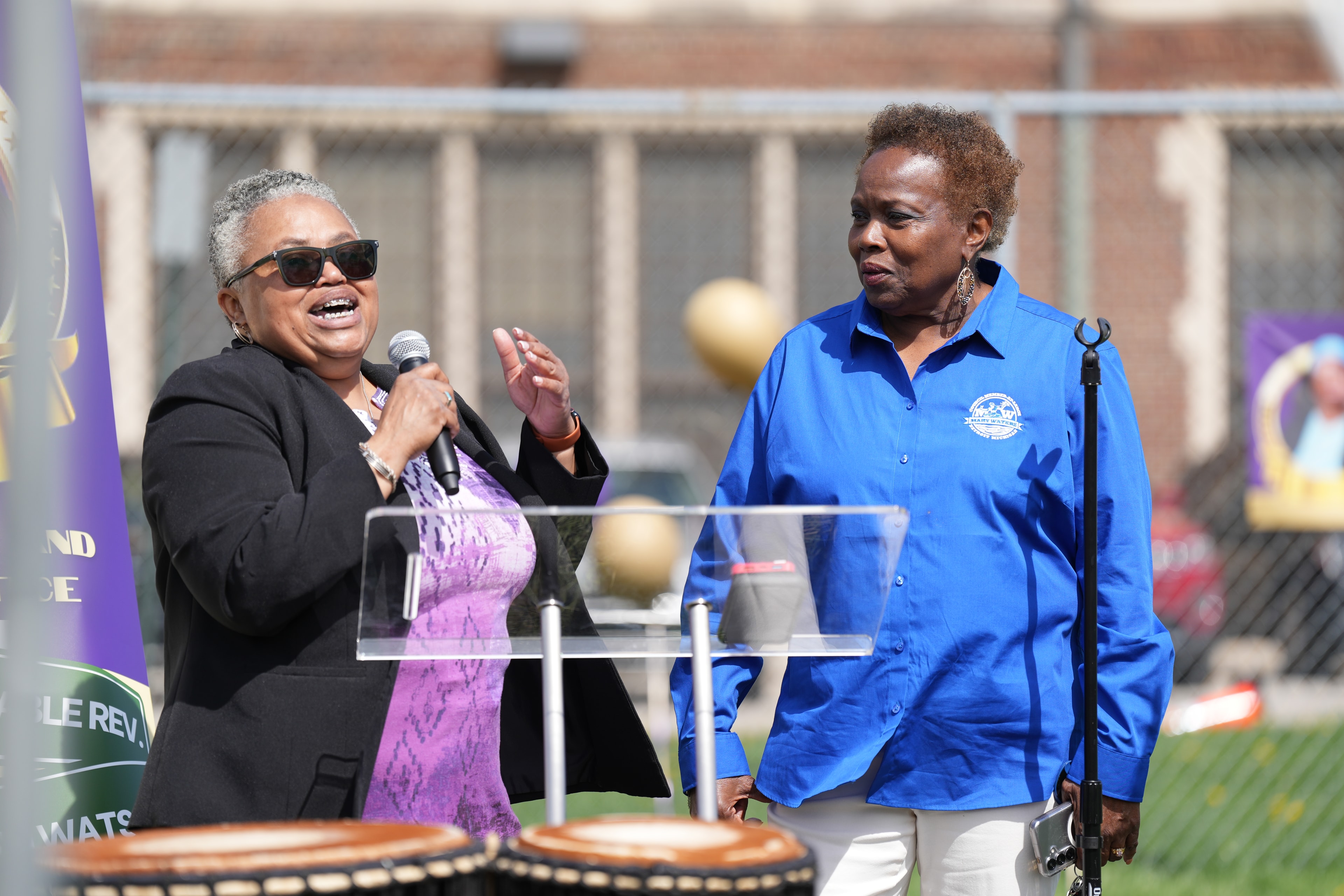 Two women speaking at outdoor event podium