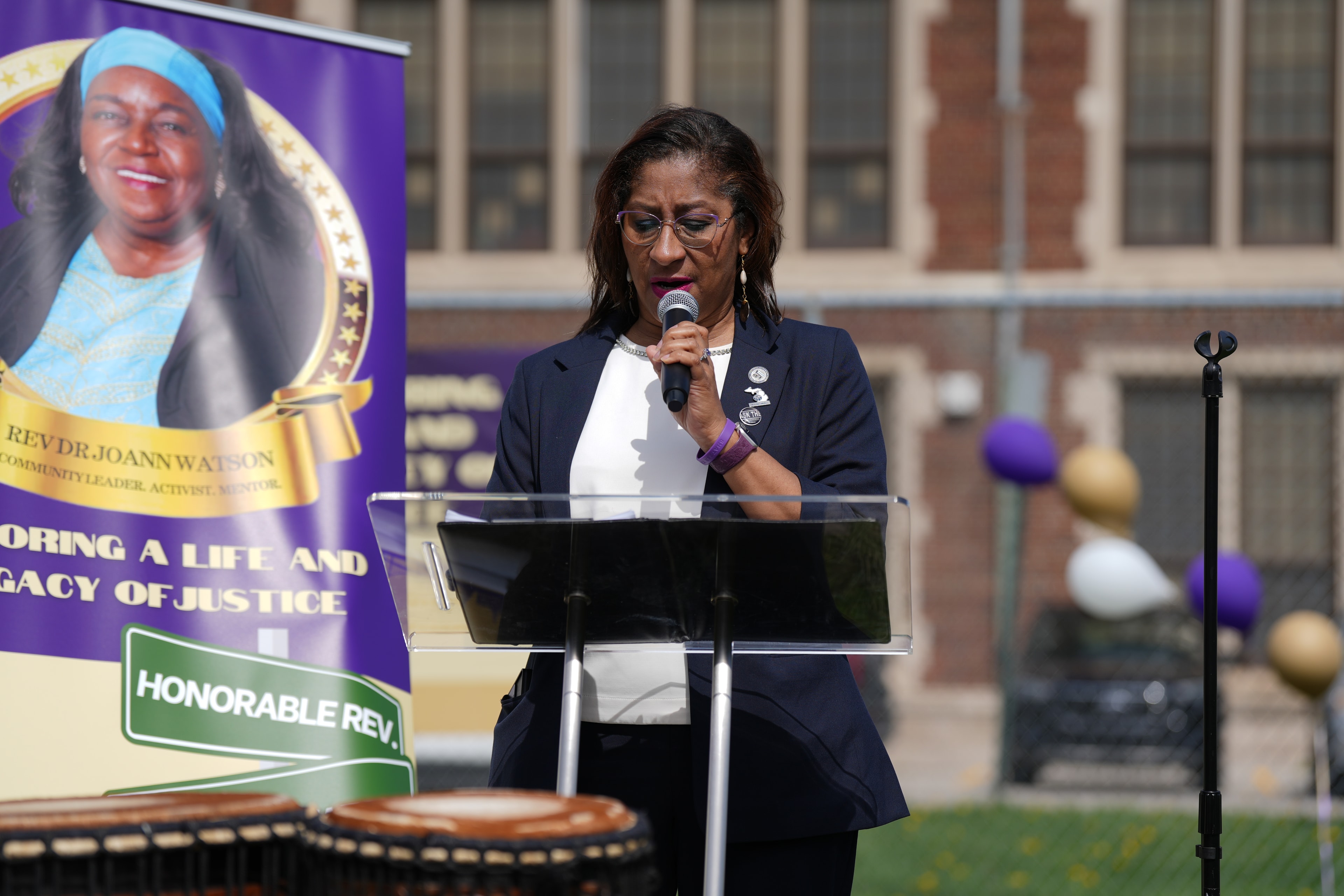 Woman speaking at podium outdoor memorial event