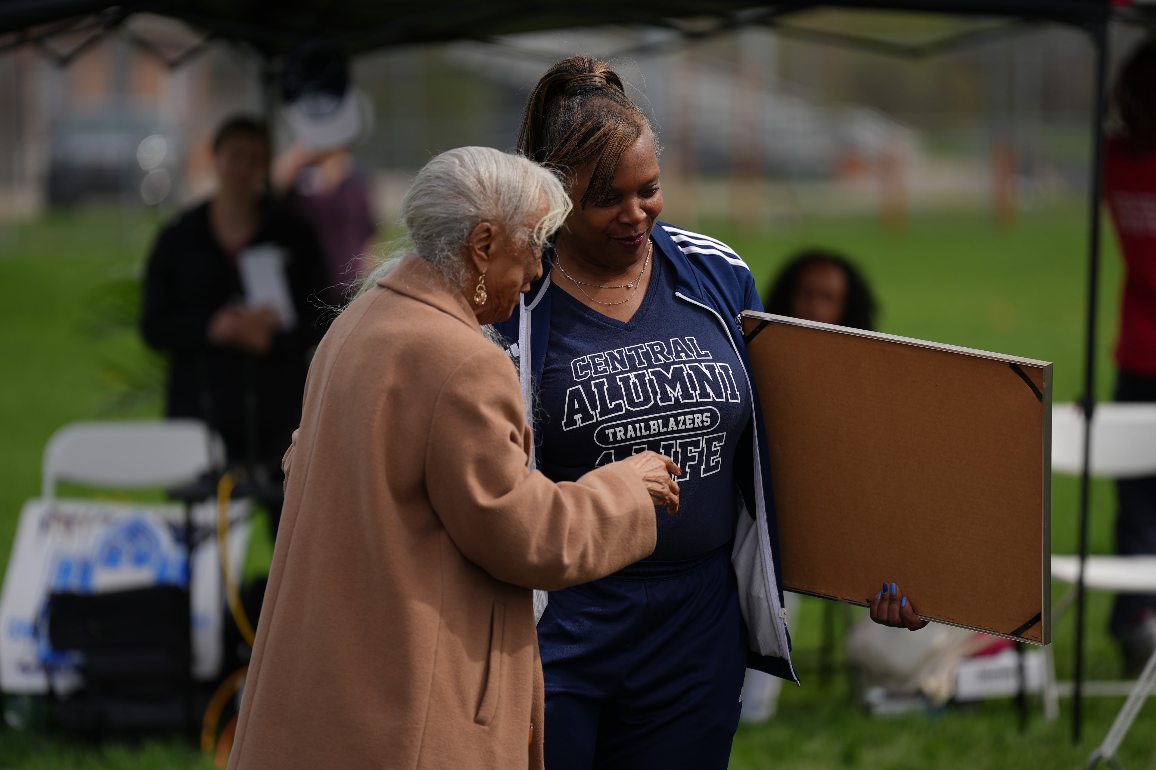 Elderly woman presenting award to young athlete