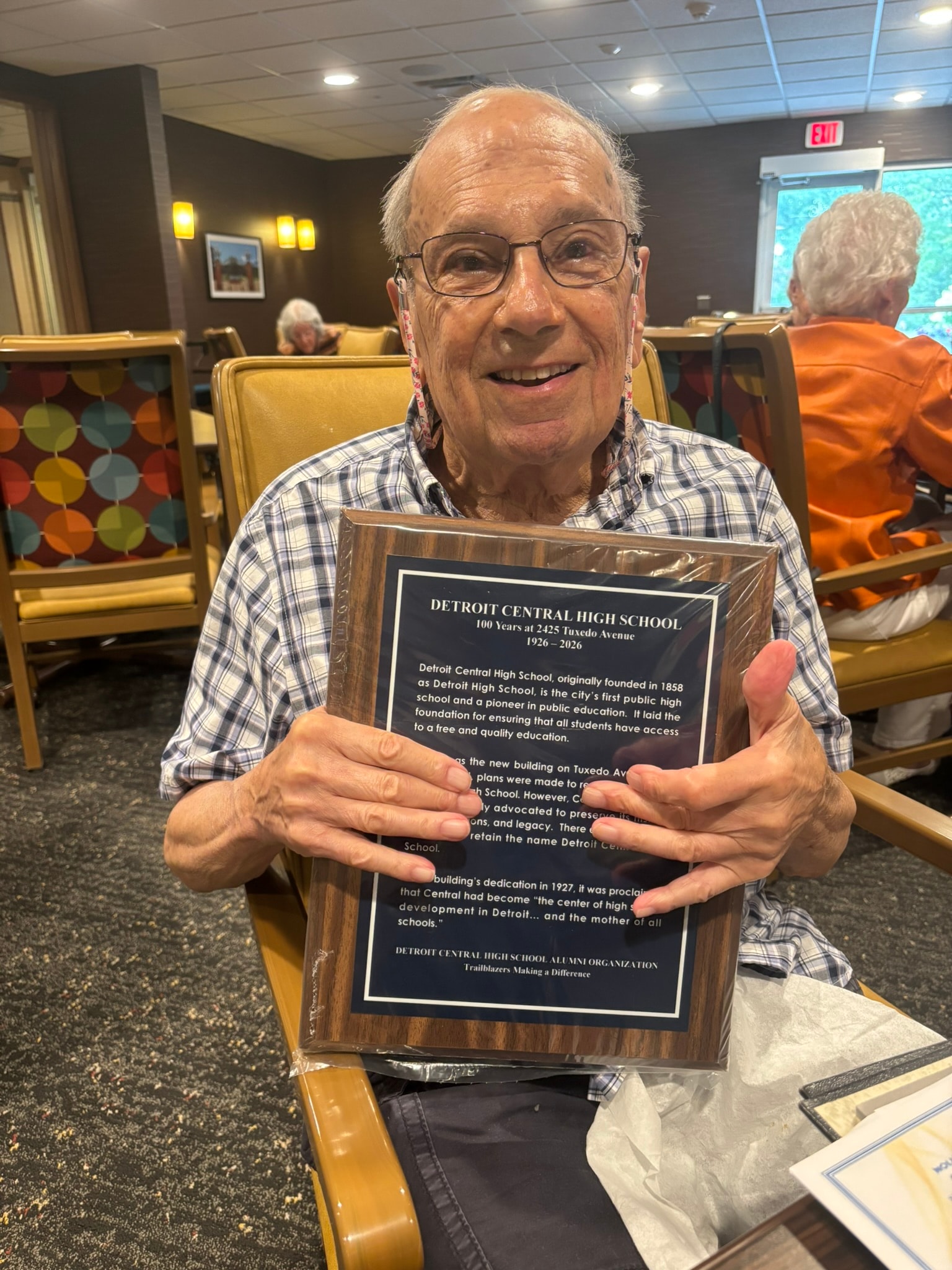 Senior man holding Detroit Central High School plaque