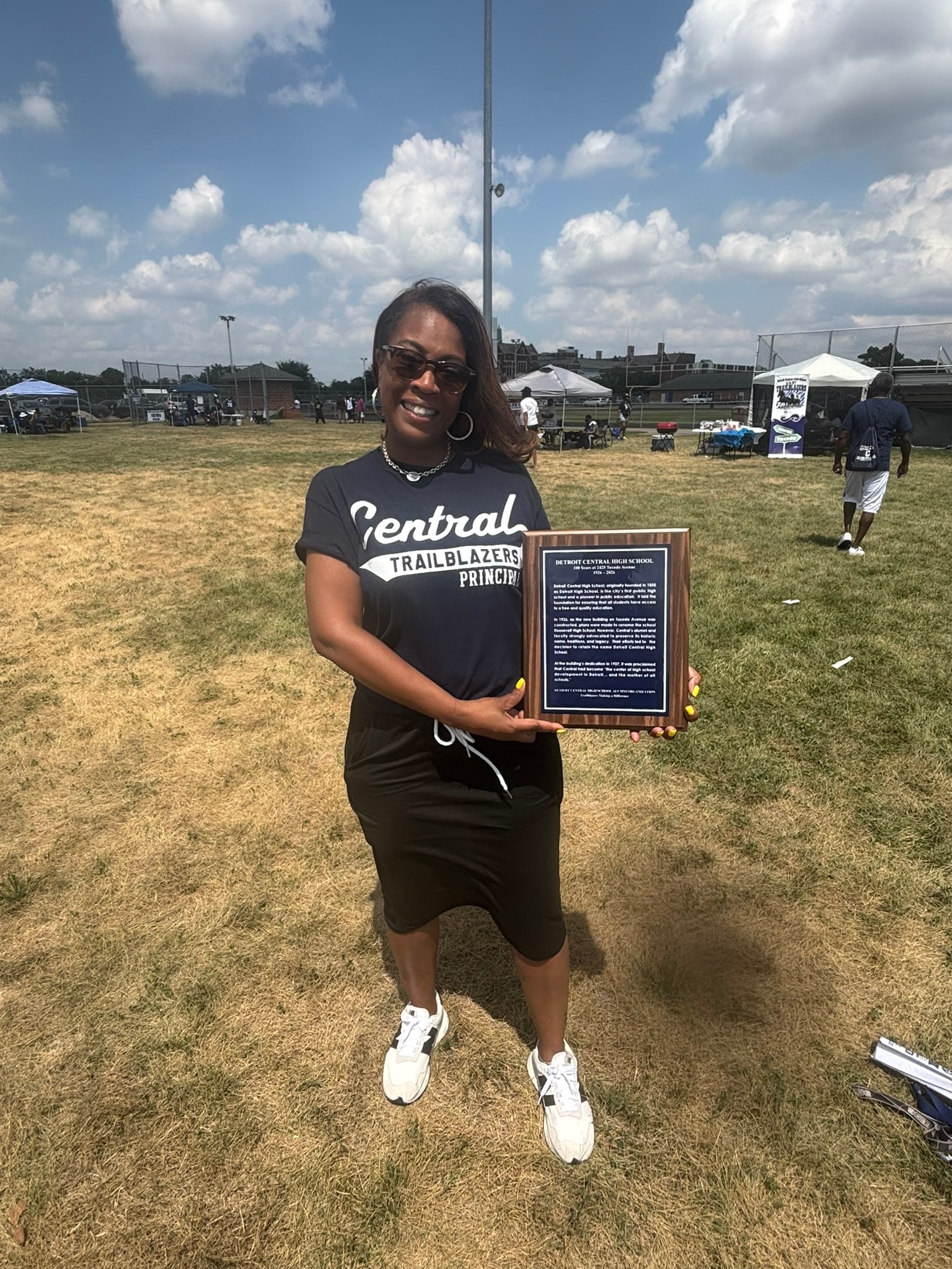 Woman holding award at baseball field
