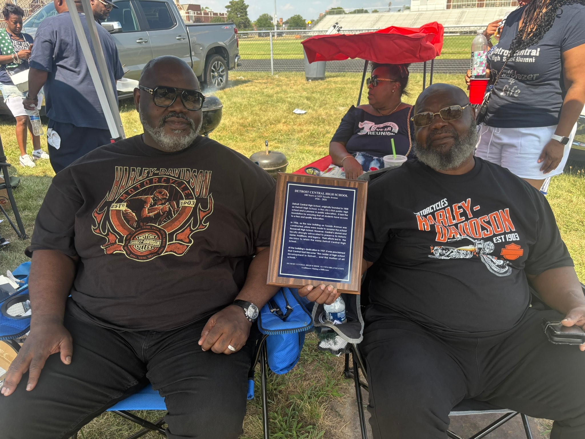 Men holding historical plaque at outdoor gathering