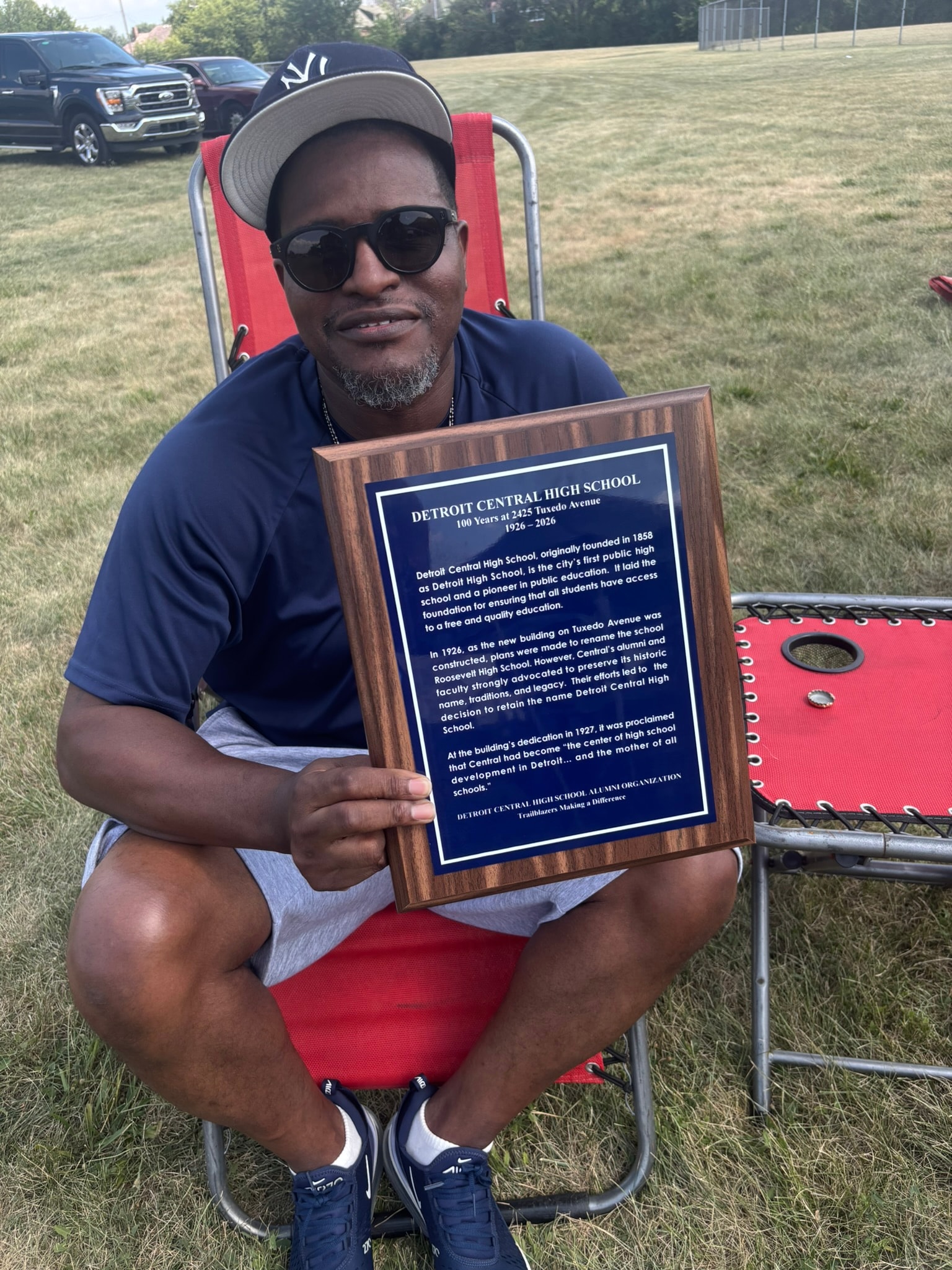 Man holding Detroit Central High School plaque outdoors