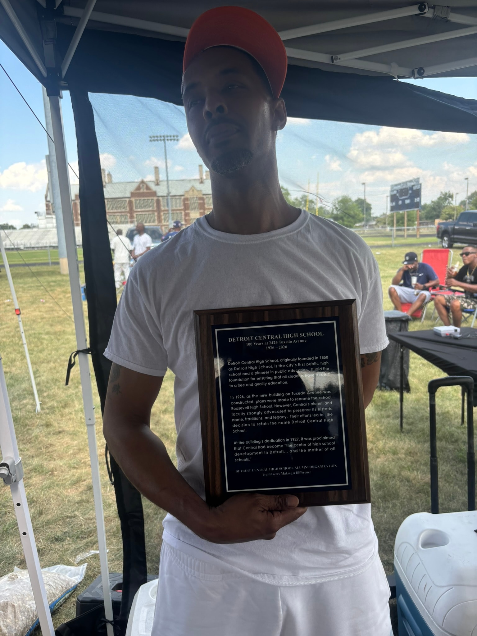 Man holding Detroit Central High School plaque outdoors