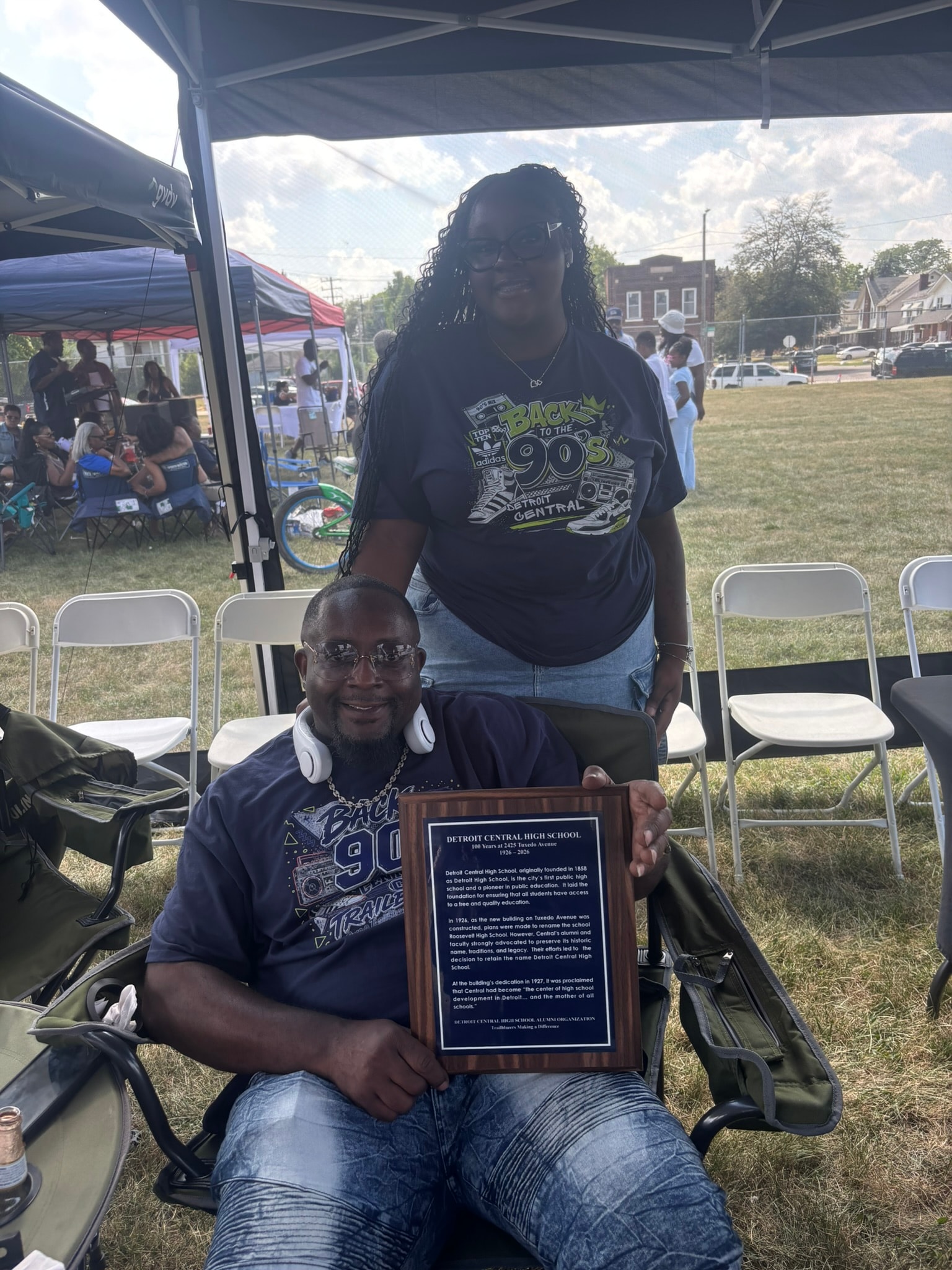 Two people holding commemorative plaque outdoors