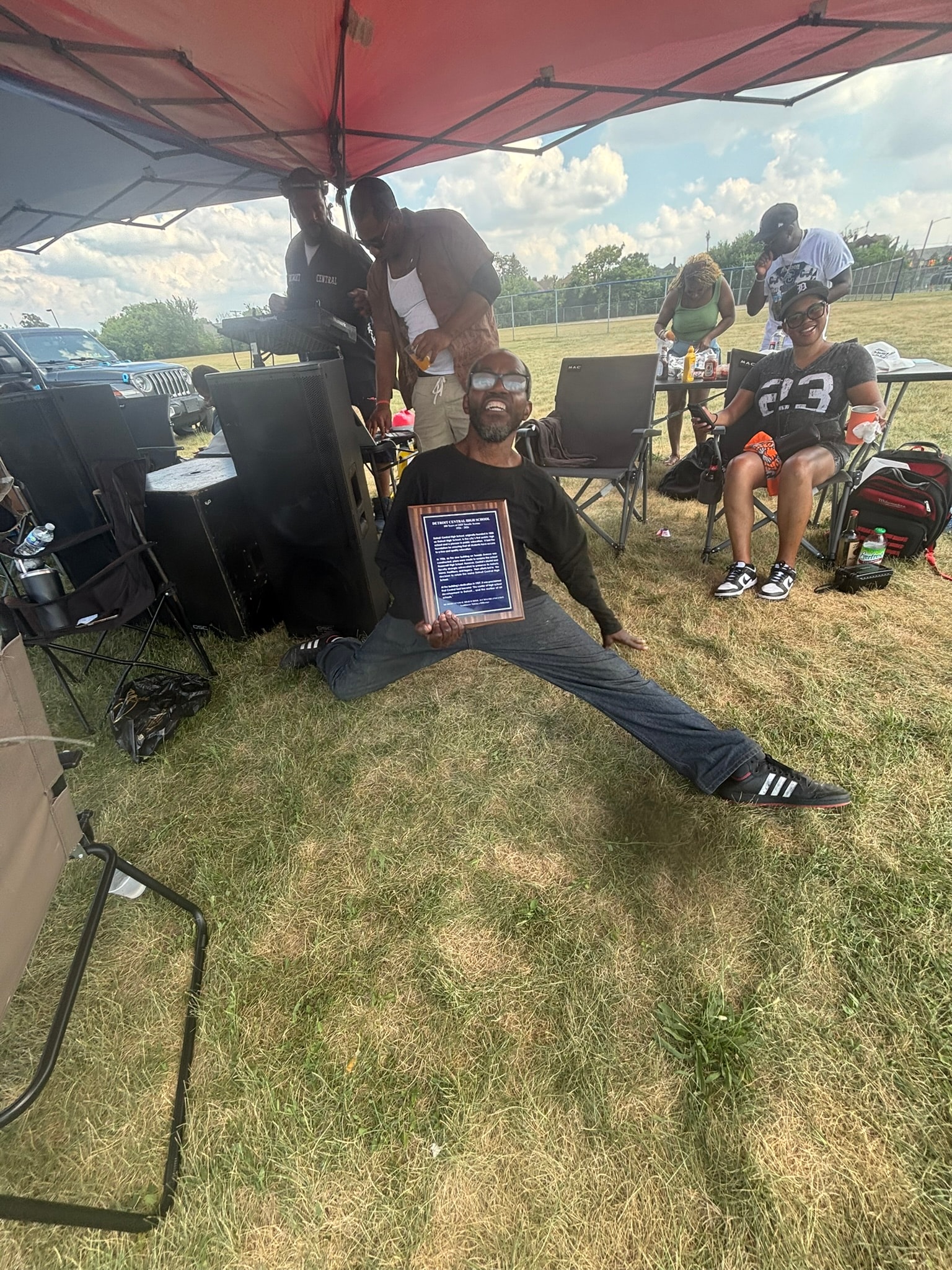 Man holding award at outdoor community gathering