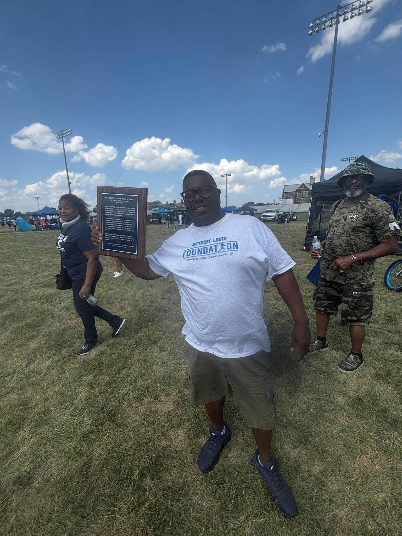 Man holding plaque at outdoor community event