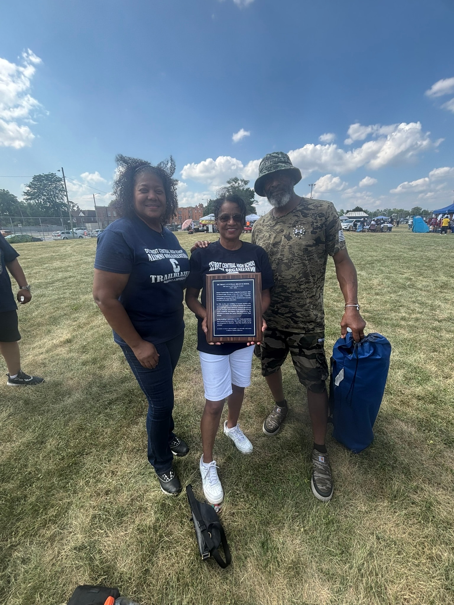 Three people holding award at outdoor event