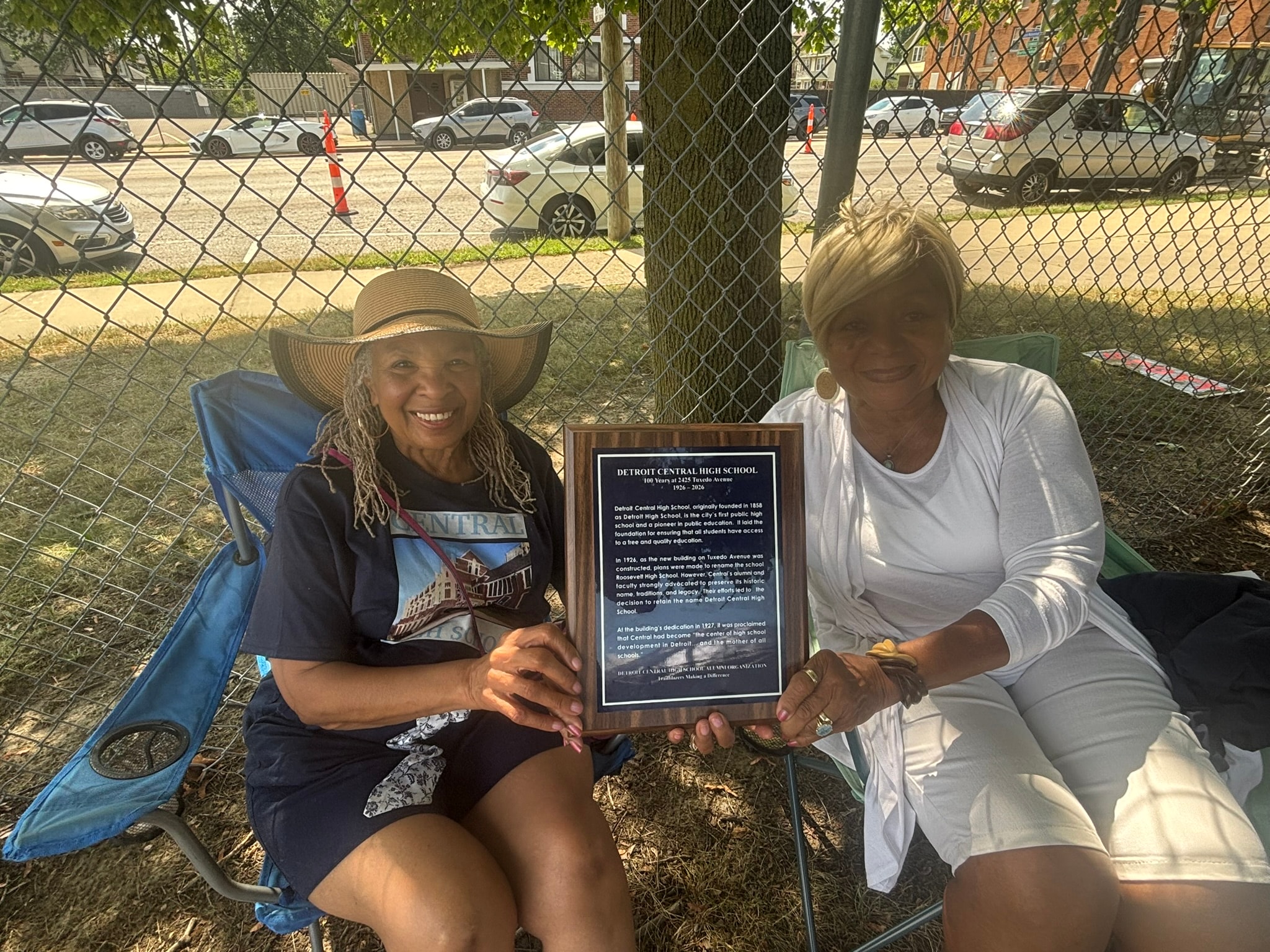 Two women holding Detroit Central High School plaque