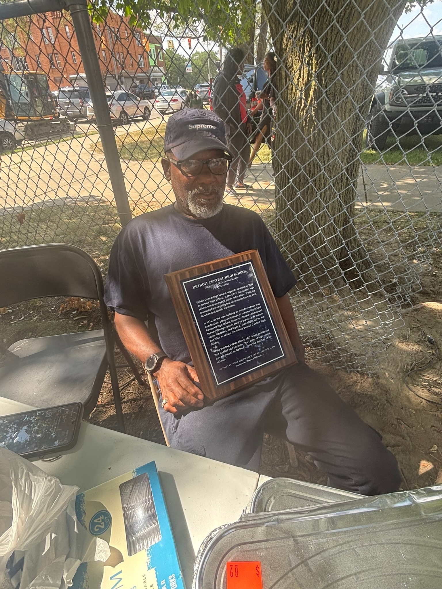Man holding wooden plaque award outdoors