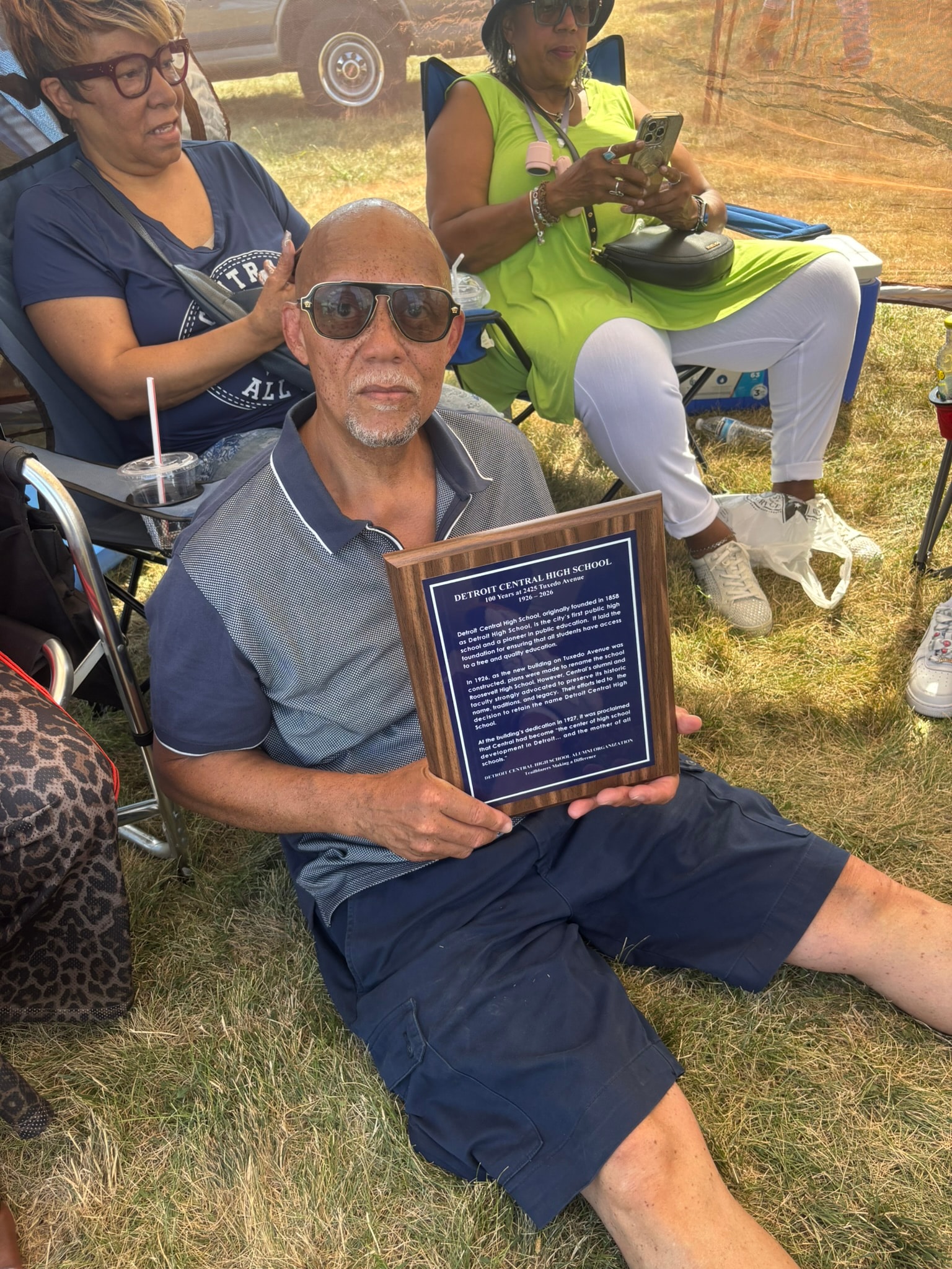 Man holding Detroit Central High School plaque outdoors