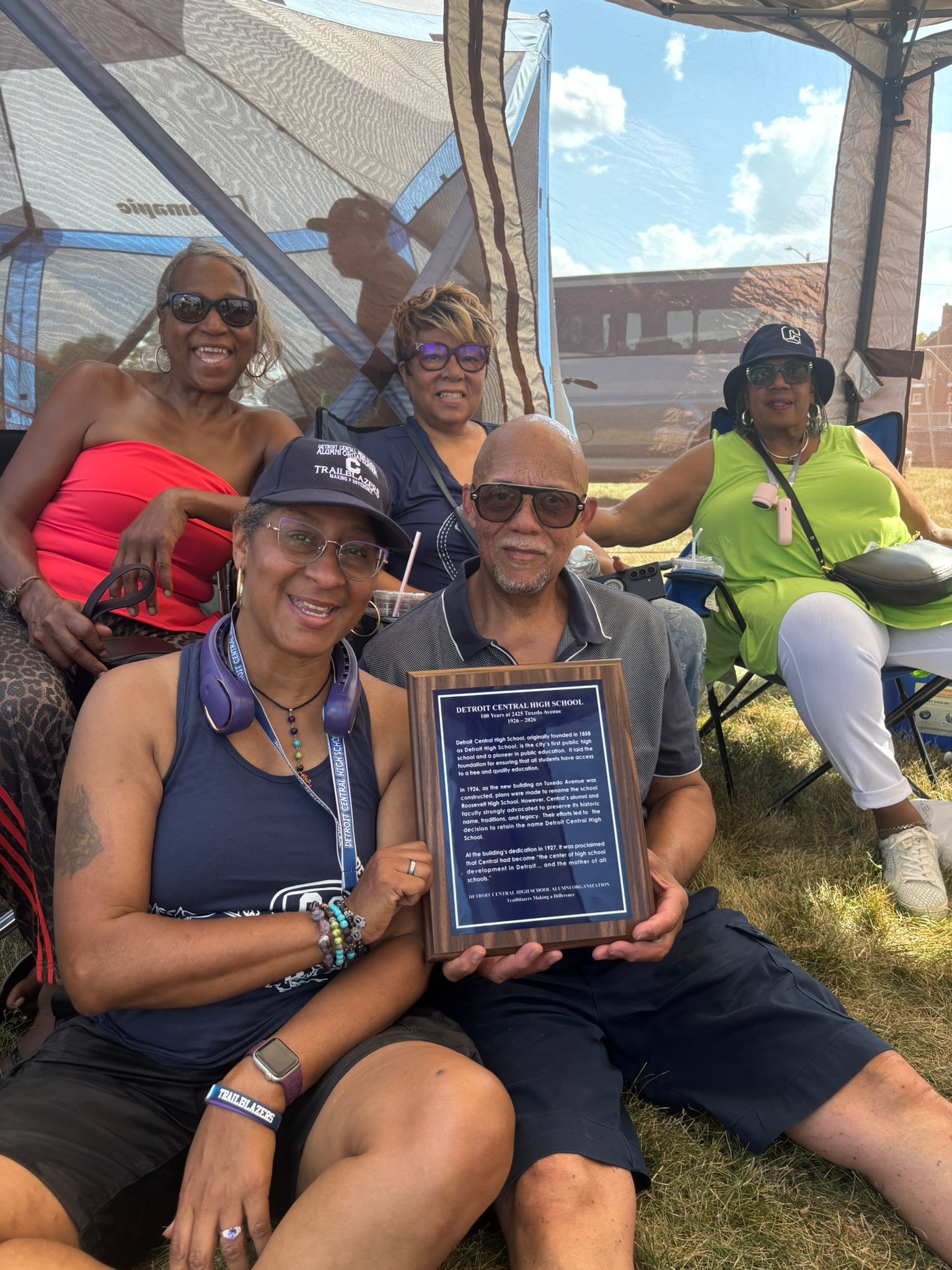 Group holding school commemorative plaque outdoors