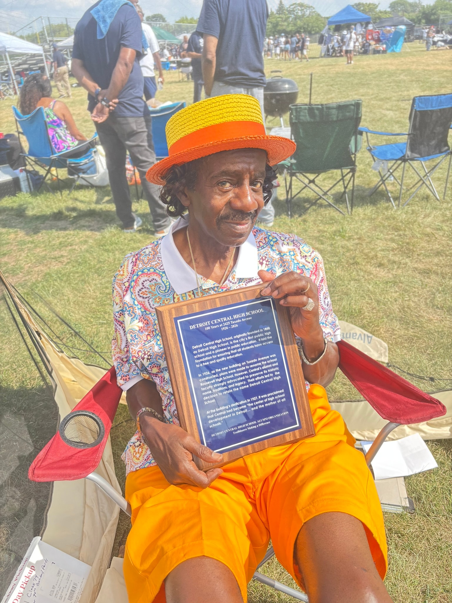 Man holding school award at outdoor event