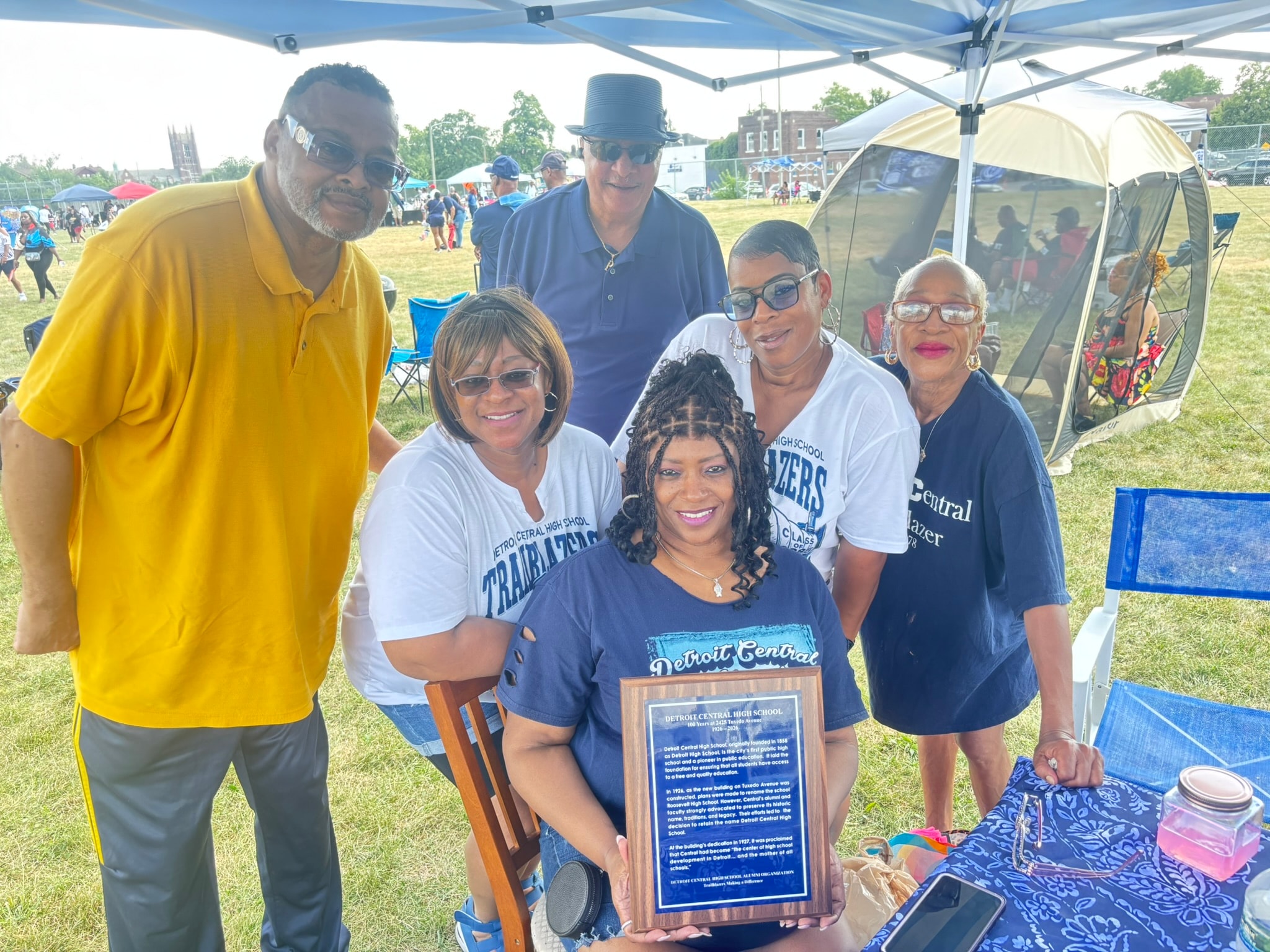 Group posing with Detroit Central High School plaque