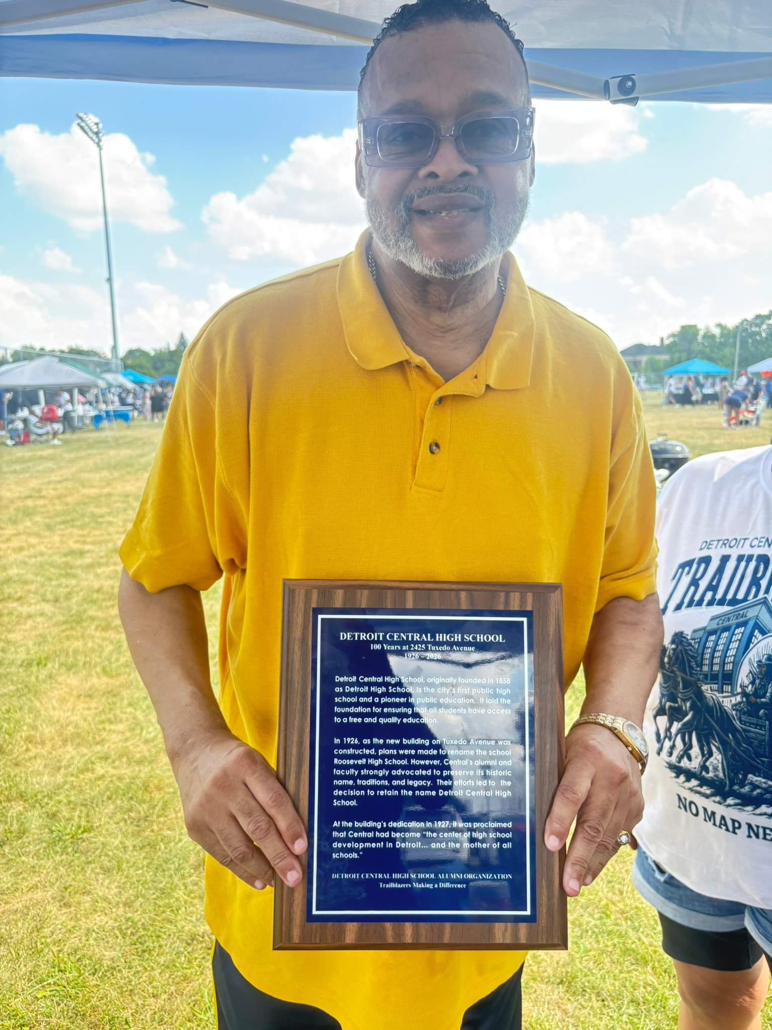 Man holding Detroit Central High School plaque outdoors