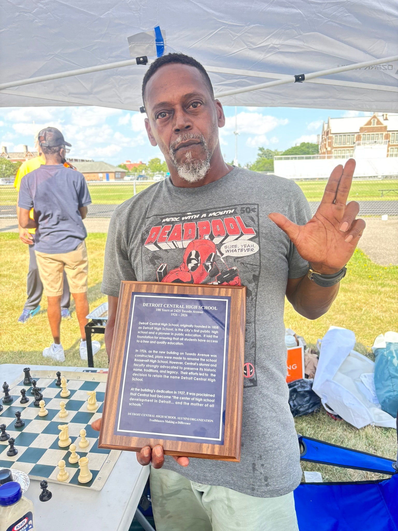 Man holding Detroit Central High School plaque outdoors