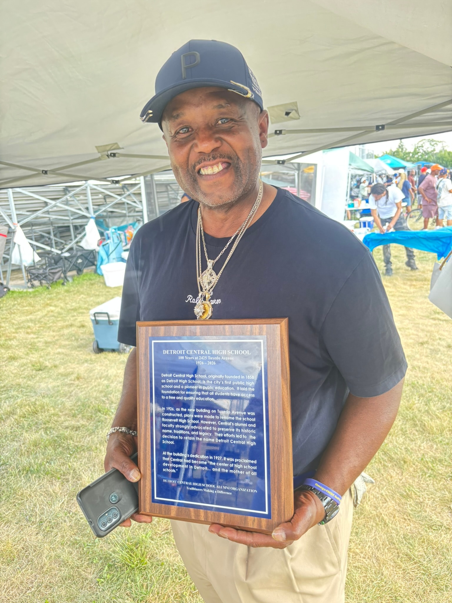 Man holding Detroit Central High School plaque outdoors
