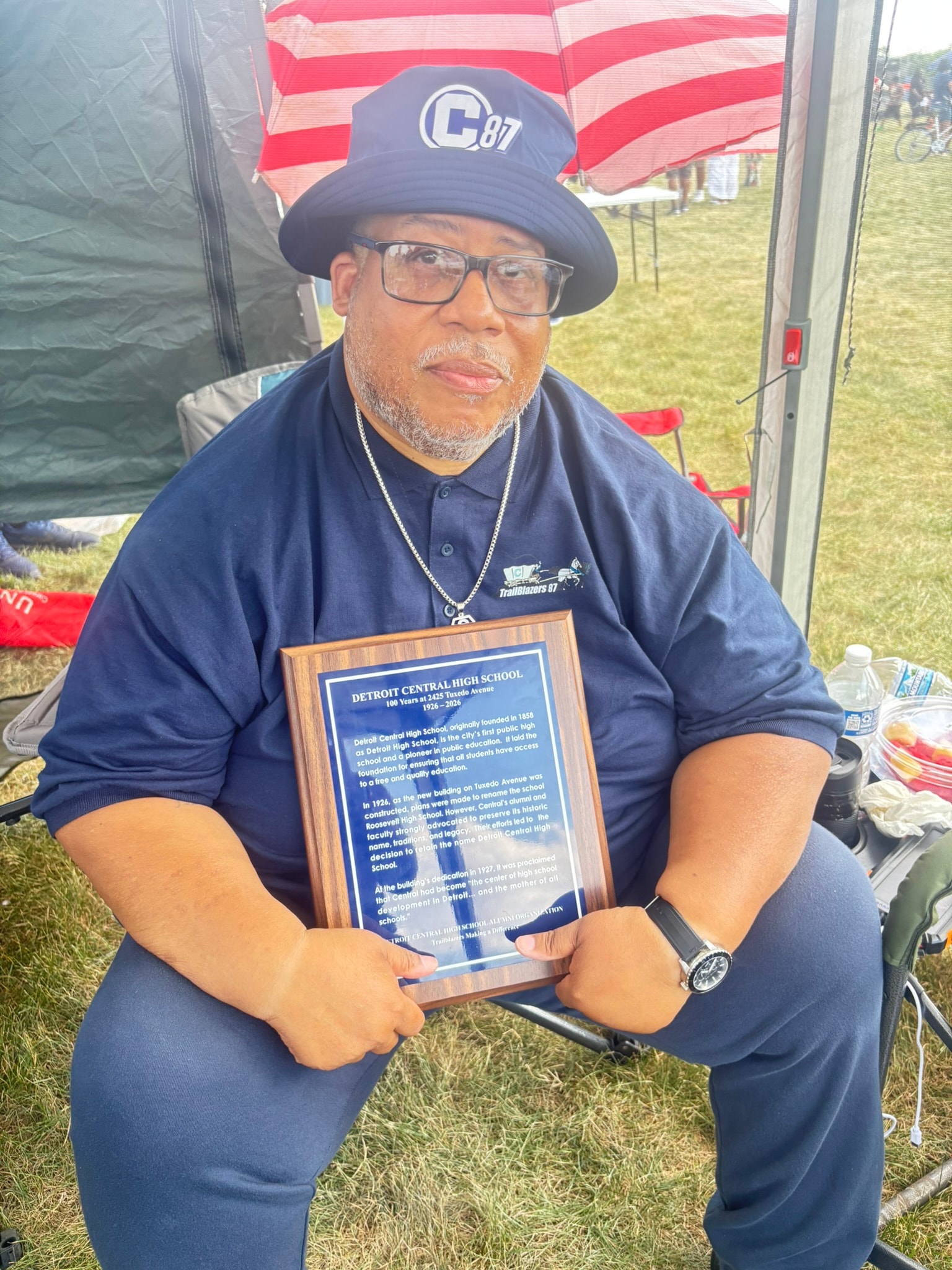 Man holding Detroit Central High School plaque outdoors