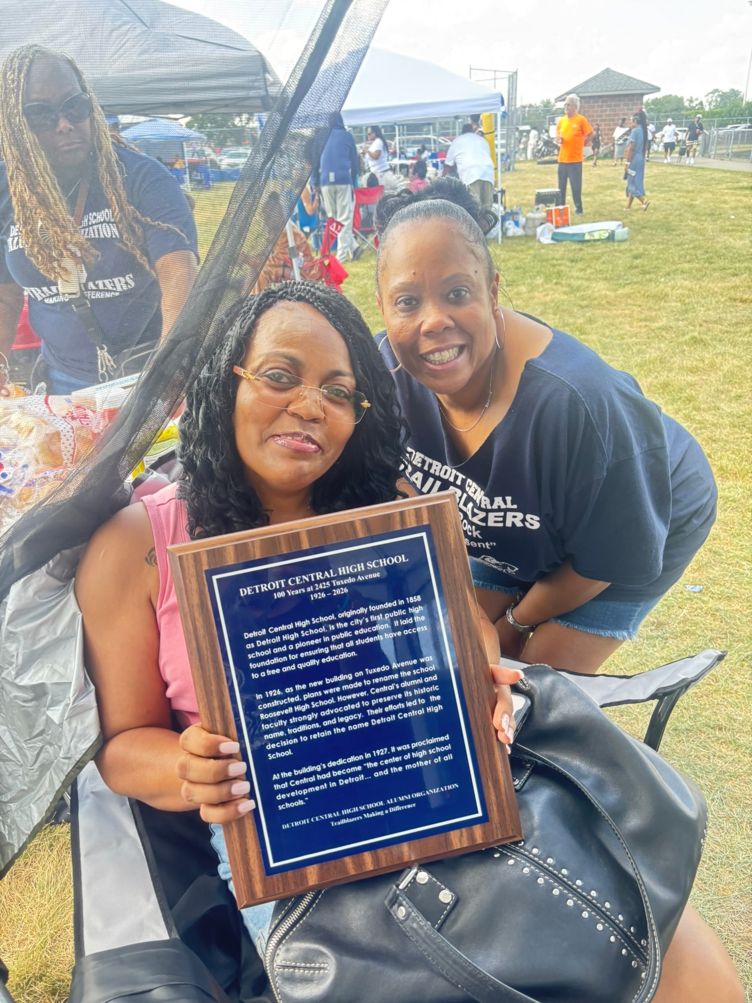 Women holding Detroit Central High School plaque