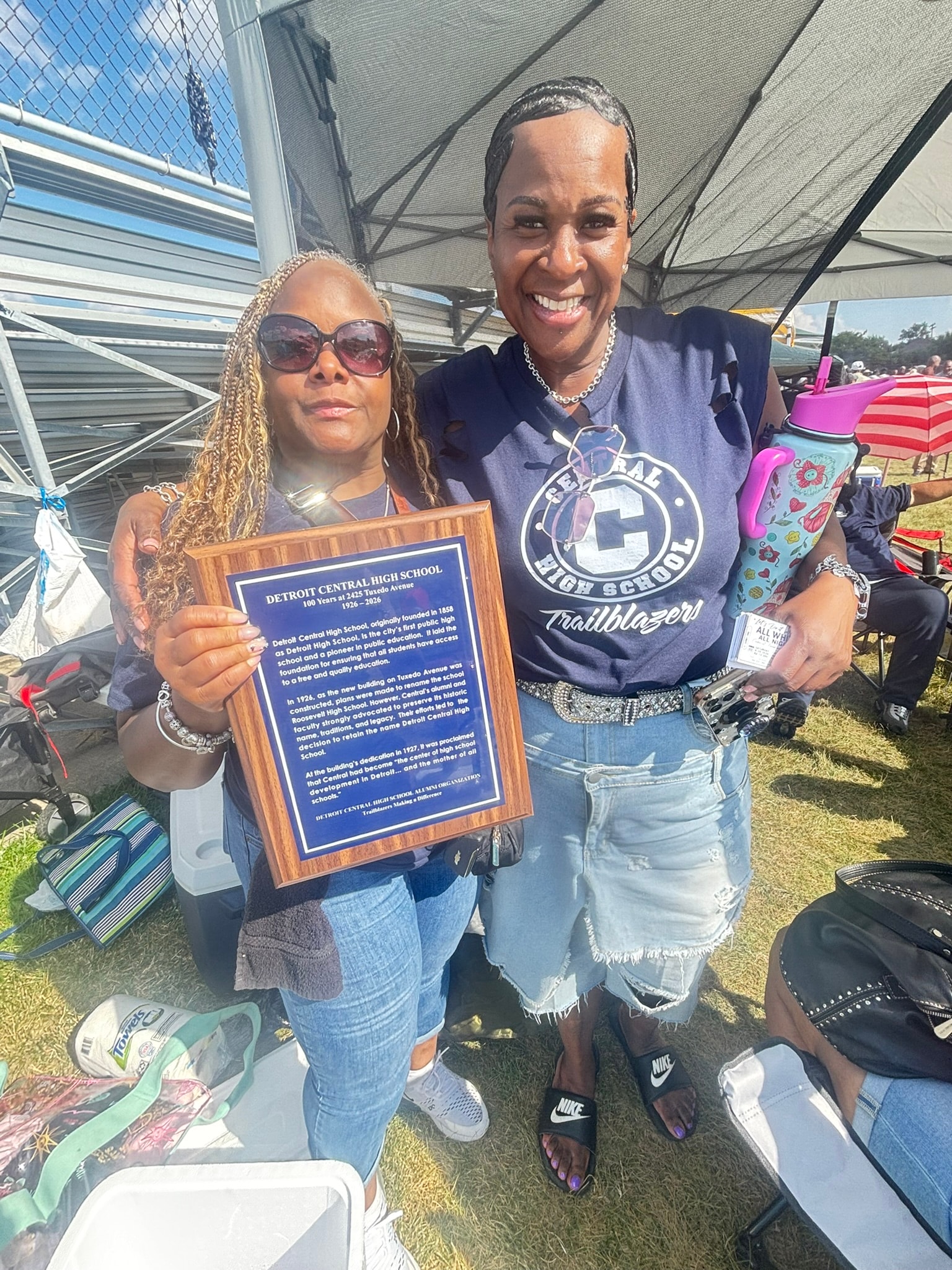 Two women holding Detroit Central High School plaque