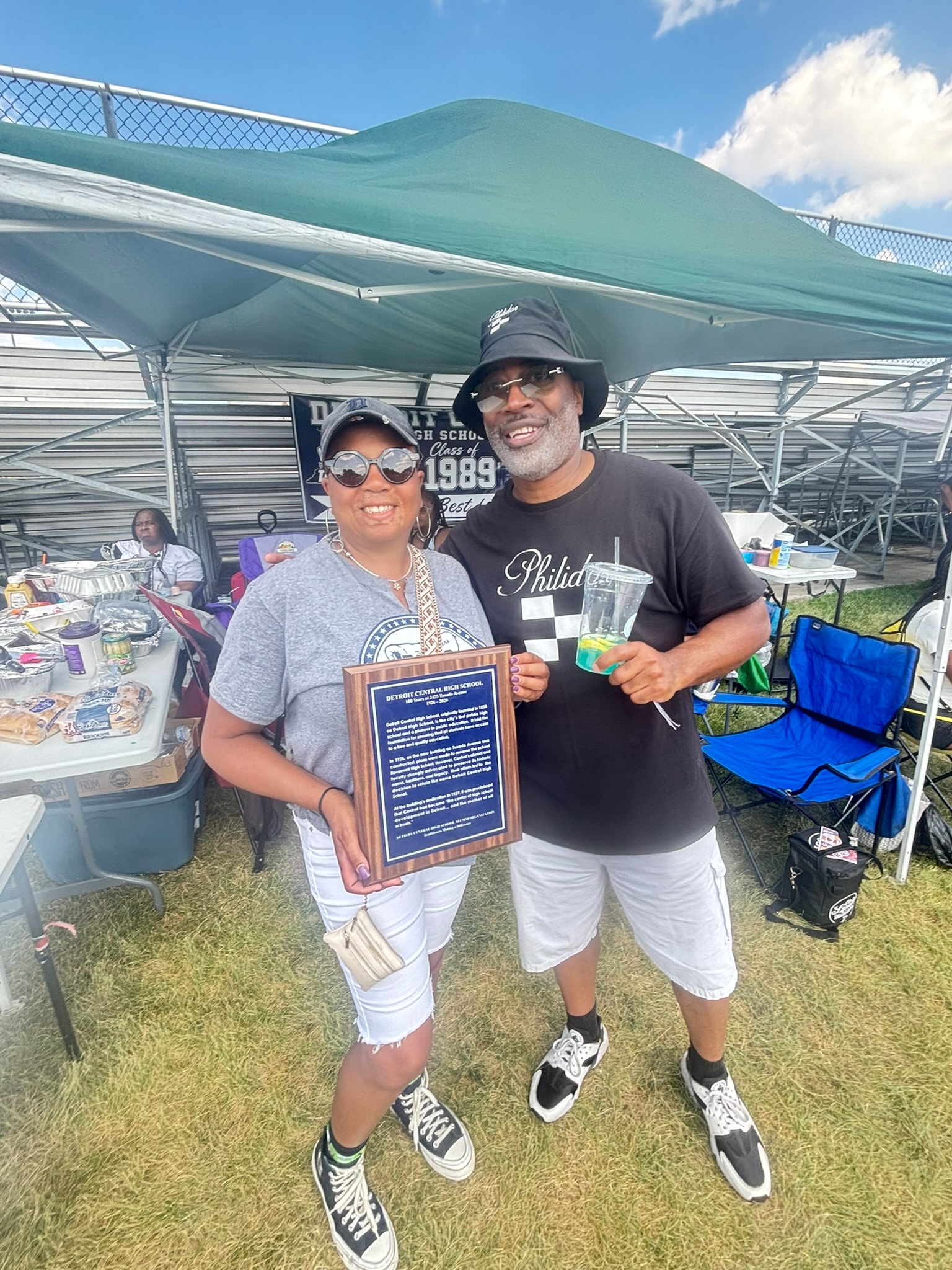 Two people holding award at outdoor reunion event