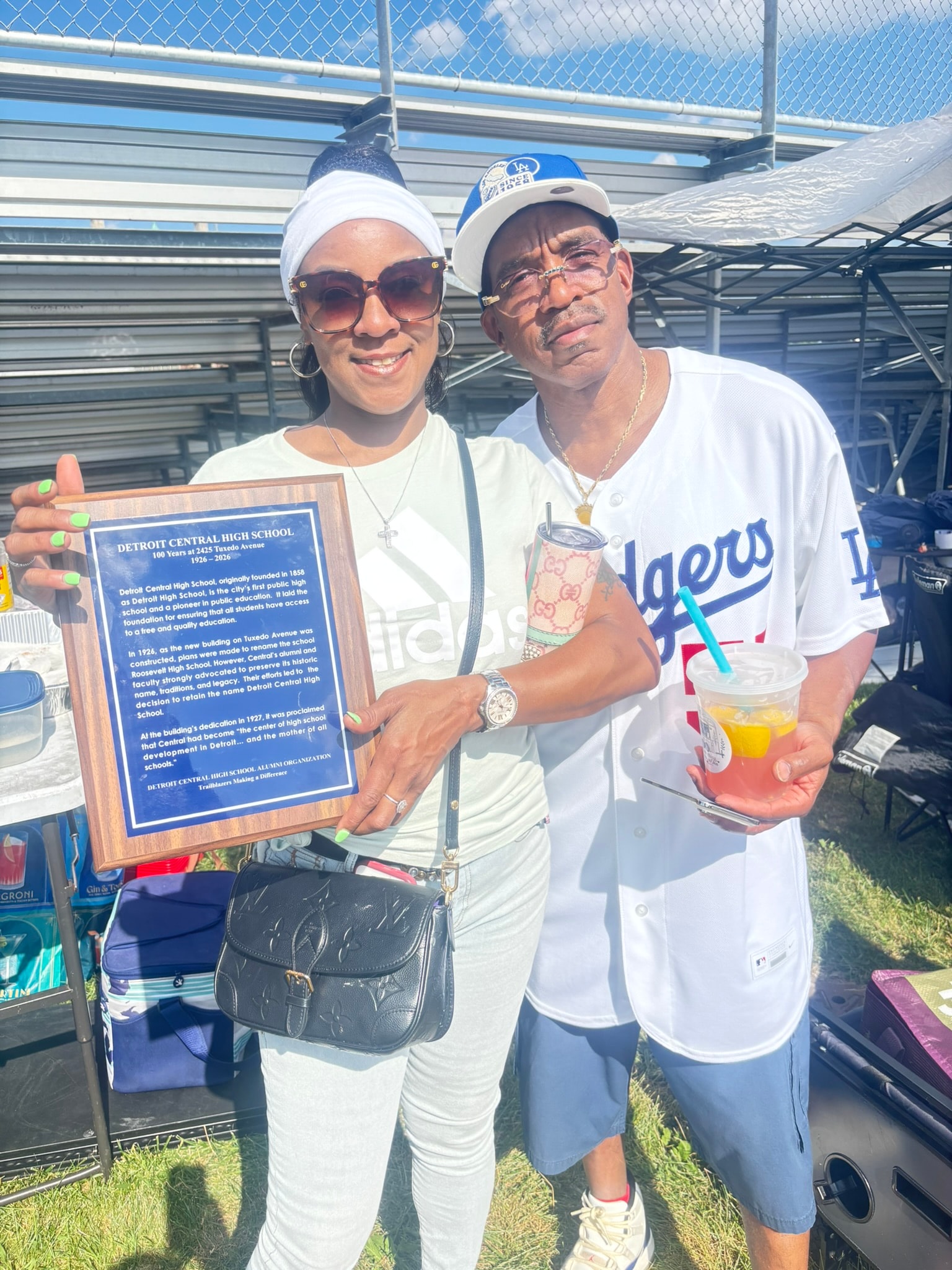 Two people holding Detroit Central High School plaque