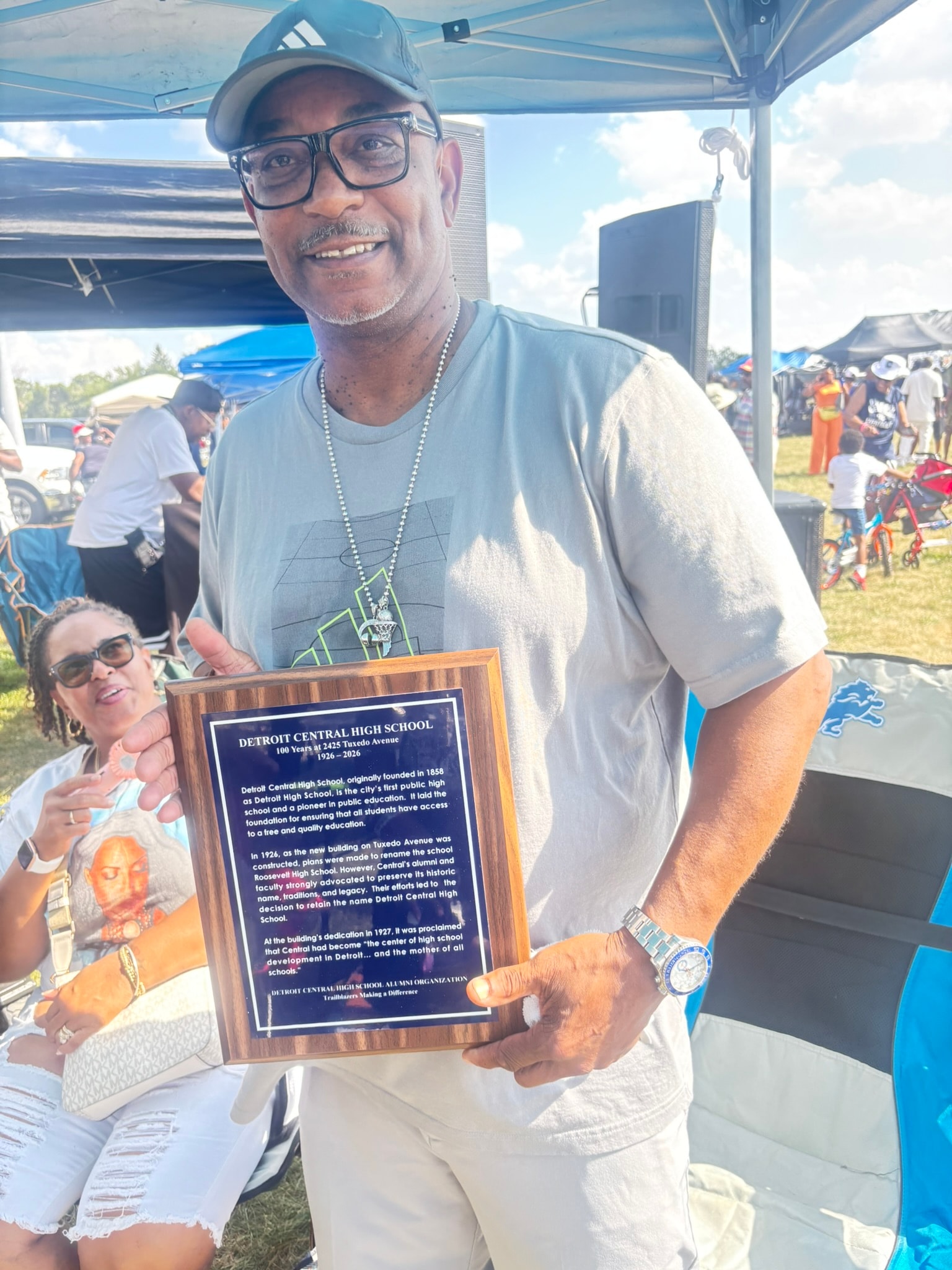 Man holding Detroit Central High School plaque outdoors
