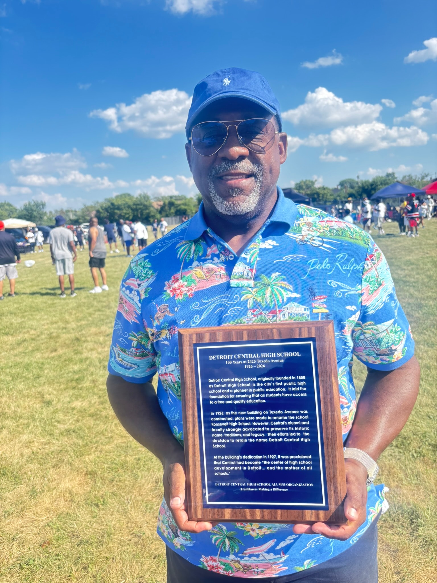 Man holding Detroit Central High School plaque outdoors
