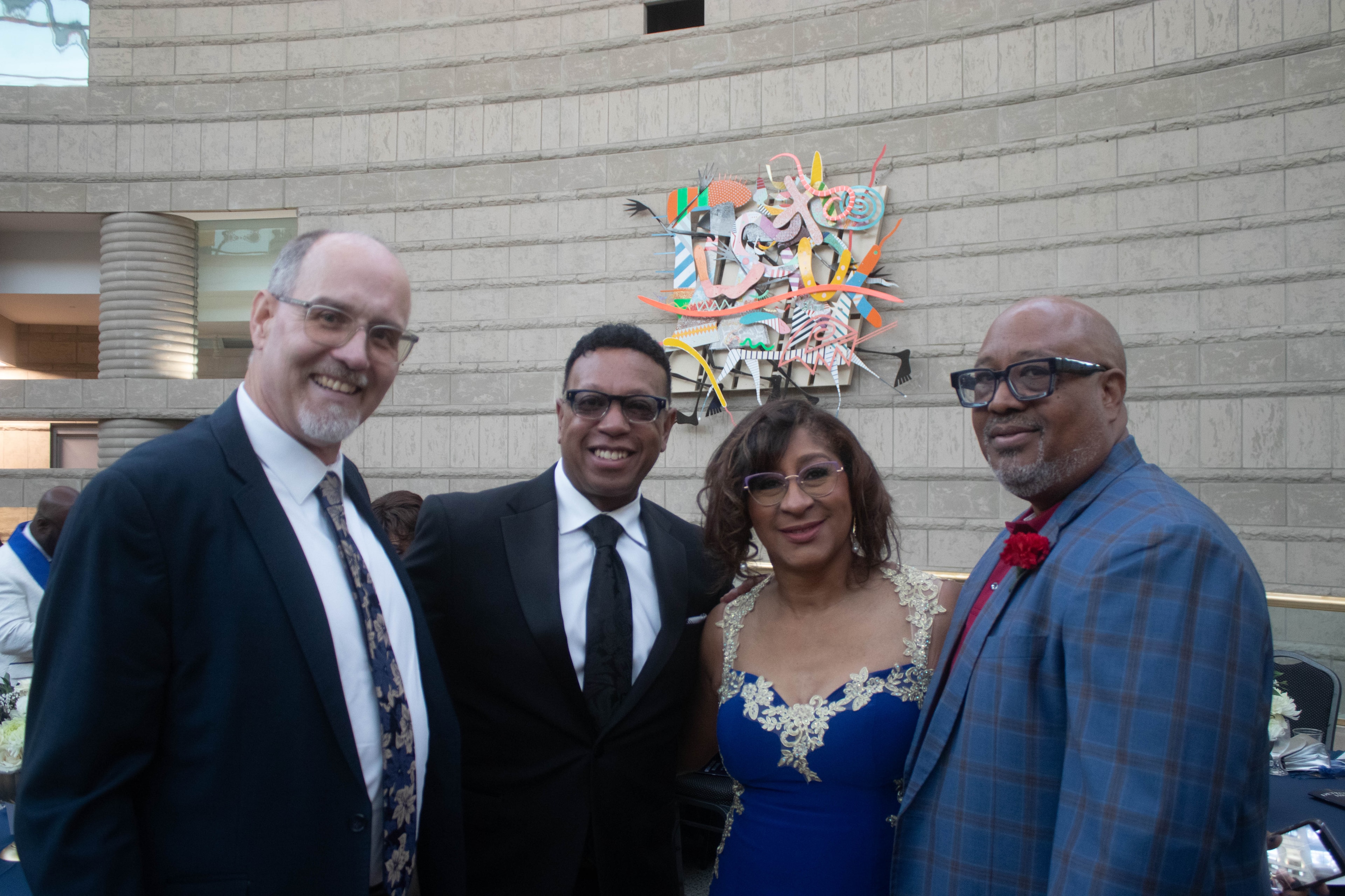 Four people posing formal event outdoor